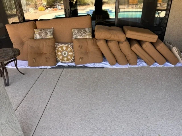 Patio cushions laid out for cleaning beside a pool